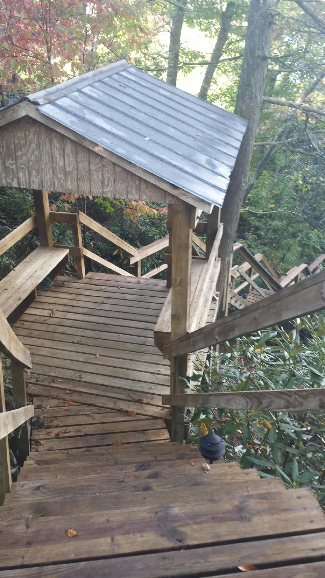 Metal roofed shelter over wooden steps on a wooded walkway — Skylight Repair & Installation work by our crew in Swanton