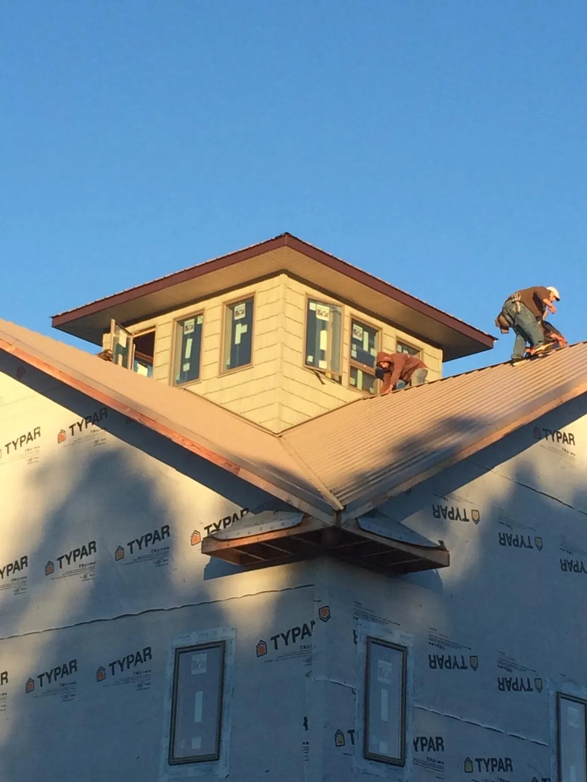 Roofers working around a rooftop cupola on a new metal roof at sunset — Roof Waterproofing in Swanton by Roofing Brothers